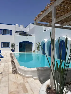 a swimming pool in front of a house at The Greek Village - Milos By Seahorse in Sowayma