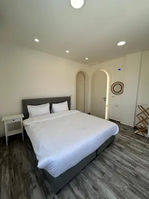 a large white bed in a bedroom with a wooden floor at The Greek Village - Milos By Seahorse in Sowayma