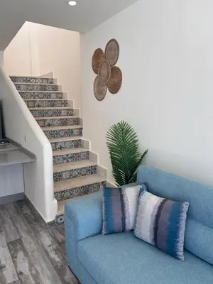 a blue couch in a living room with a staircase at The Greek Village - Milos By Seahorse in Sowayma