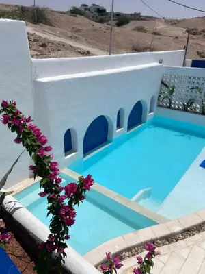 a blue swimming pool with purple flowers in front of it at The Greek Village - Cofru By Seahorse in Sowayma