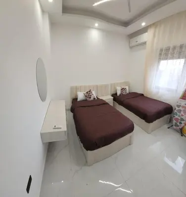 a bedroom with two beds and a desk in it at شقة مفروشة بغرفتين نوم وصالة و حمامين in Amman