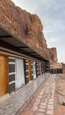 a building next to a cliff with a mountain at Ali with the stars in Wadi Rum