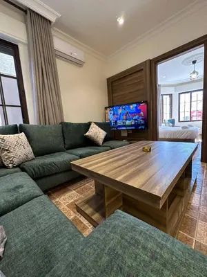 a living room with a green couch and a wooden table at 1 Antica Jabalal-lwebdeh in Amman