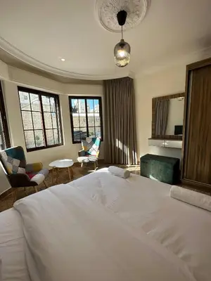 a bedroom with a large white bed and a living room at 1 Antica Jabalal-lwebdeh in Amman