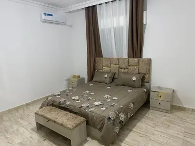 a bedroom with a bed with a brown comforter at Airport Road شارع المطار in Al Yādūdah