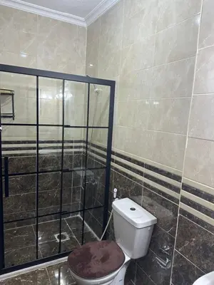 a bathroom with a toilet and a glass shower at Airport Road شارع المطار in Al Yādūdah