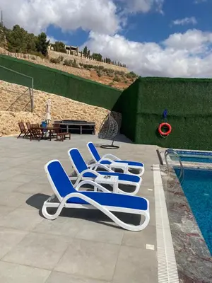 a row of lounge chairs next to a swimming pool at Makanak Villas in Jerash