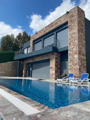 a house with a swimming pool with two lawn chairs at Makanak Villas in Jerash