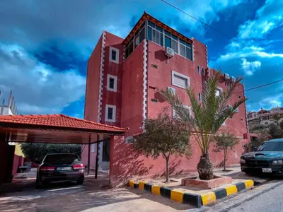 a red building with a palm tree in front of it at Petra Friends House in Petra