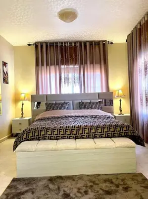 a bedroom with a large bed and two lamps at Classy 3 Bedroom Apartment in Amman in Ţāb Kirā‘