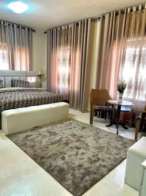 a bedroom with a bed and a table with a rug at Classy 3 Bedroom Apartment in Amman in Ţāb Kirā‘