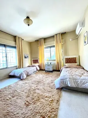 a bedroom with two beds and a large rug at Classy 3 Bedroom Apartment in Amman in Ţāb Kirā‘