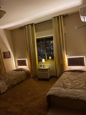 a hotel room with two beds and a window at Classy 3 Bedroom Apartment in Amman in Ţāb Kirā‘
