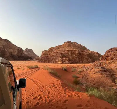 a car driving through the desert with mountains at Wadi rum magical in Wadi Rum