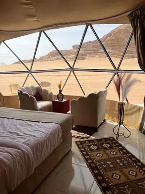 a bedroom with a bed and a view of the desert at RADISSON lUXURY RUM CAMP in Wadi Rum