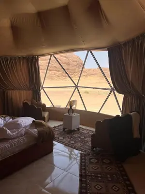 a bedroom with a bed and a large window at RADISSON lUXURY RUM CAMP in Wadi Rum