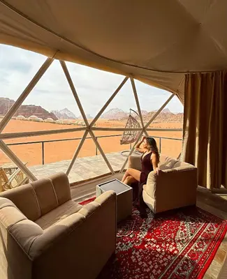 a woman sitting on a couch in front of a window at RADISSON lUXURY RUM CAMP in Wadi Rum
