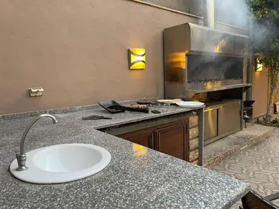 a kitchen with a grill and a counter with a sink at Yasmina Chalet in Al Kafrayn