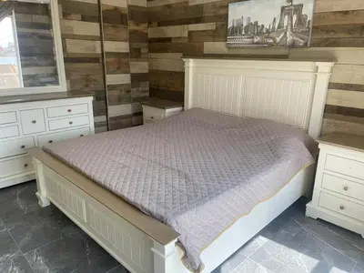 a bedroom with a white bed and wooden walls at Yasmina Chalet in Al Kafrayn