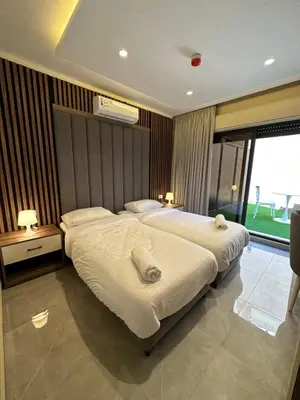 a bedroom with two beds and a large window at Chic Apartments For Rent ave0-2 in Umm Uthainah