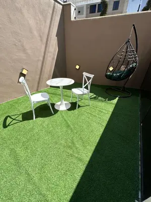 a patio with a table and two chairs and a swing at Chic Apartments For Rent ave0-2 in Umm Uthainah