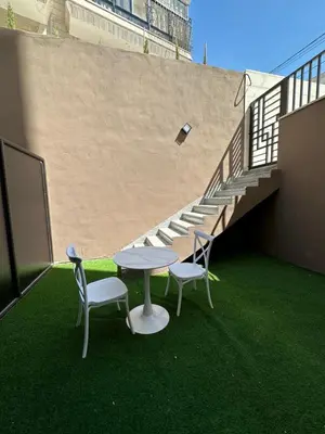 a table and two chairs and a table and stairs at Chic Apartments For Rent ave0-2 in Umm Uthainah