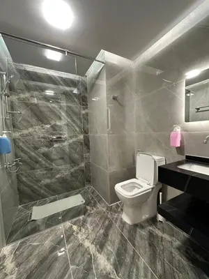 a bathroom with a toilet and a glass shower at Chic Apartments For Rent ave0-4 in Umm Uthainah