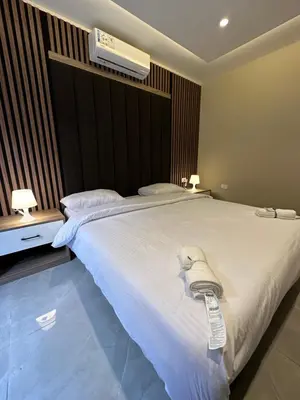 a bedroom with a large white bed with a air conditioner at Chic Apartments For Rent ave0-4 in Umm Uthainah