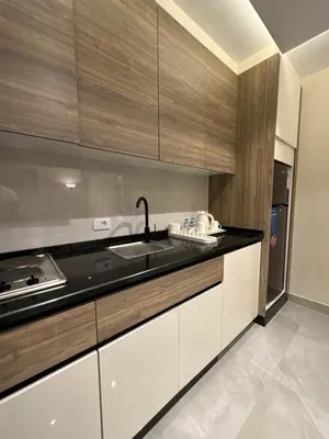 a kitchen with white cabinets and a black counter top at Chic Apartments For Rent ave0-6 in Amman