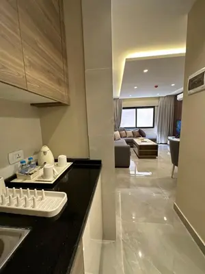 a kitchen with a black counter top and a living room at Chic Apartments For Rent ave0-7 in Umm Uthainah