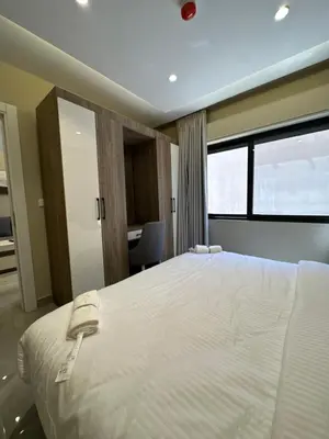 a bedroom with a large white bed and a window at Chic Apartments For Rent ave0-7 in Umm Uthainah