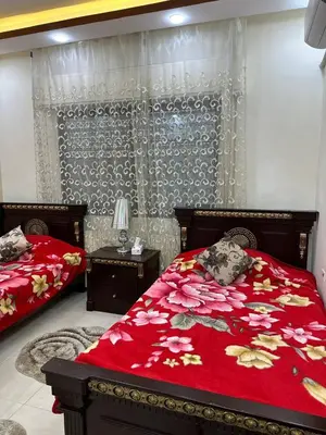 a bedroom with two beds and a red comforter at شقة مفرشة في الرابية 3 غرف نوم in Amman