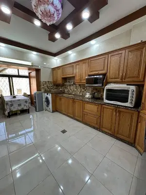 a large kitchen with wooden cabinets and appliances at شقة مفرشة في الرابية 3 غرف نوم in Amman