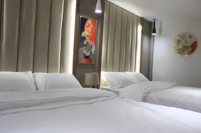 two beds in a bedroom with white sheets at Azmal Hotel & Suites in Irbid