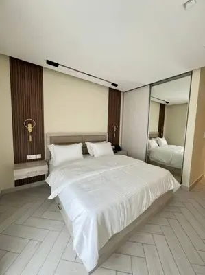 a bedroom with a large white bed and a mirror at Luxury Apt with Private Beach In Ayla in Aqaba