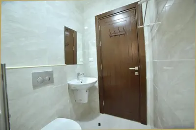 a bathroom with a toilet and a wooden door at رمّ للأجنحة Rum Royal Suites in Irbid