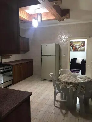 a kitchen with a refrigerator and a table and chairs at شقةارضية فاخرة مفروشة عمان ضاحية الرشيد in Ţāb Kirā‘