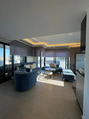 a living room with blue couches and tables and windows at The Roof Top Lounge in Umm Uthainah