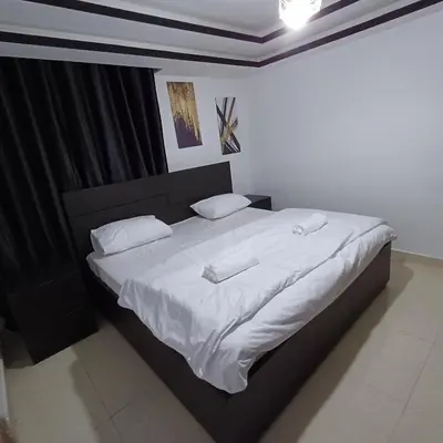 a bedroom with a large bed with white sheets and pillows at Laperla family apartment 1 in Al Yādūdah