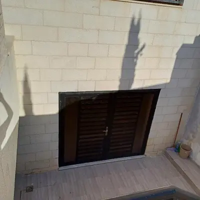 a garage with a brown door and a brick wall at Laperla family apartment 1 in Al Yādūdah