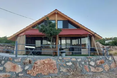 a house with a stone wall in front of it at أكواخ وشقق كرم العنب عجلون in ‘Ayn Jannā