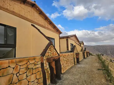 a building with a stone wall next to a road at Ramses Tafilah Lodge نزل رمسيس الطفيلة in At-Tafilah
