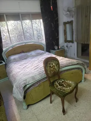 a bedroom with a bed and a chair and a window at Al Otaibi in Umm Uthainah