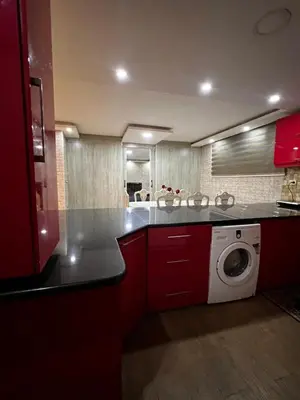 a kitchen with red cabinets and a washing machine at شقة للإجار في الجاردنز in ‘Urjān al Gharbīyah