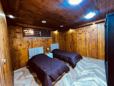 two beds in a room with wooden walls at شقة للإجار في الجاردنز in ‘Urjān al Gharbīyah