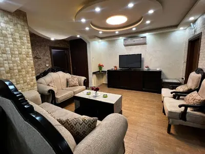 a living room with couches and a flat screen tv at شقة للإجار في الجاردنز in ‘Urjān al Gharbīyah