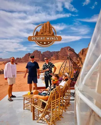 a group of people sitting in rocking chairs in the desert at RUM WINGS BUBBLES lUXURY CAMP in Wadi Rum