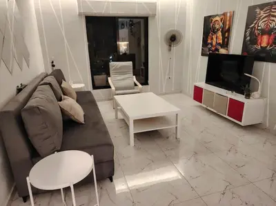 a living room with a couch and a table and a tv at Cozy modern 2 bedroom apartment in Amman