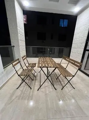 two chairs and a wooden table in a room at Modern & New 3-BR Entire Apt - Prime Location! in Rujm ash Sharāʼirah