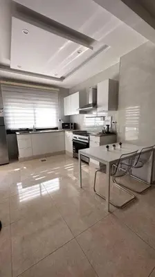 a kitchen with a table and two chairs in it at Modern & New 3-BR Entire Apt - Prime Location! in Rujm ash Sharāʼirah